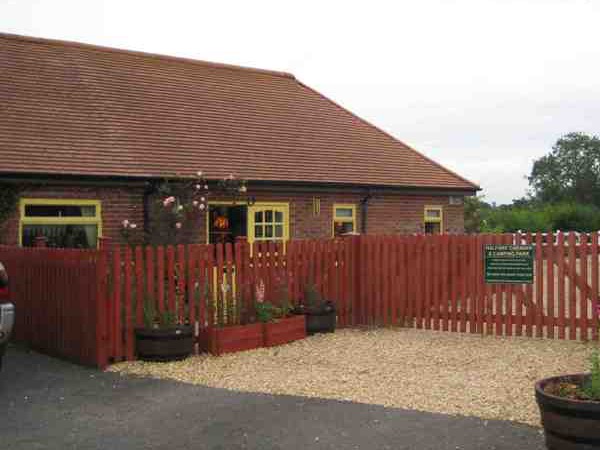 The park entrance, with a red brick building behind a red picket fence and tubs of flowers